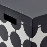 Une boîte noire avec des découpes géométriques, mettant en valeur un savoir-faire de haute qualité et des matériaux recyclés robustes.