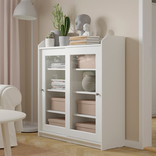 Boîte de rangement TJOG blanche sur parquet avec porte-étiquette en métal.