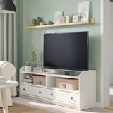 Salon moderne avec télévision sur pied, décoré de plantes et de photos.