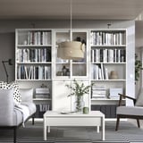 Espace de vie moderne avec étagères et canapé TONSTAD blanc cassé, au design élégant avec des portes en verre et des accents en bois.