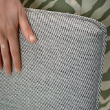 Une main tenant un échantillon de tissu texturé gris, mettant en valeur son tissage doux et durable avec une légère texture, idéal pour les housses de meubles.