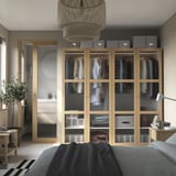 Chambre moderne en chêne avec armoire TONSTAD, portes vitrées, éclairage et meubles assortis en gris doux et noir.