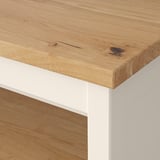 Gros plan d’une table TORNVIKEN avec un plateau en chêne naturel avec une texture de grain visible et une finition lisse et brillante.