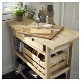 Chariot de cuisine en bois avec planches à découper, huile végétale et caisses en bois.