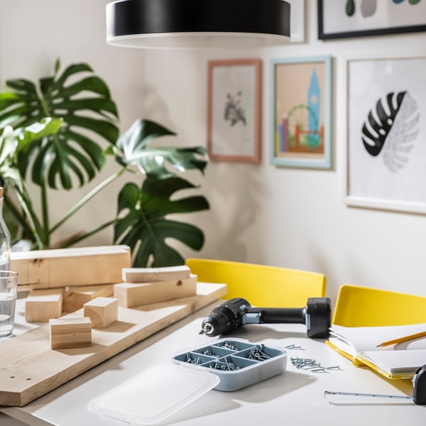 Petite boîte de bricolage avec des vis près de la perceuse sur le bureau.