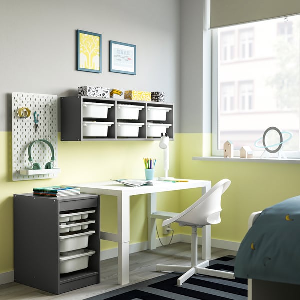 Chambre d’enfants avec rangement TROFAST blanc, bas et gris, s’adaptant sous le bureau, plateaux organisés pour les petits objets, compact mais spacieux.