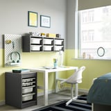 Chambre d’enfants avec rangement TROFAST blanc, bas et gris, s’adaptant sous le bureau, plateaux organisés pour les petits objets, compact mais spacieux.