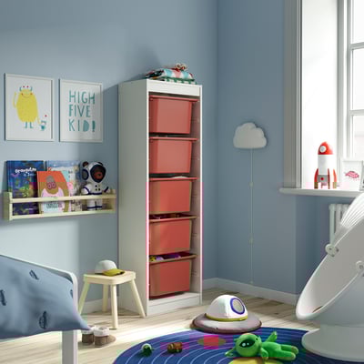 Chambre d’enfant avec rangements rouges TROFAST, murs bleu clair, meubles blancs, décoration sur le thème de l’espace et jouets.