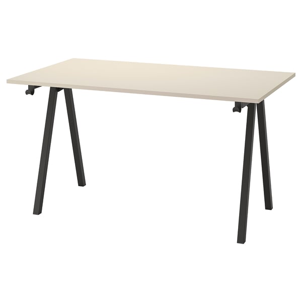 Un bureau TROTTEN avec un plateau beige clair et des pieds en métal noir, avec un design en forme de A.