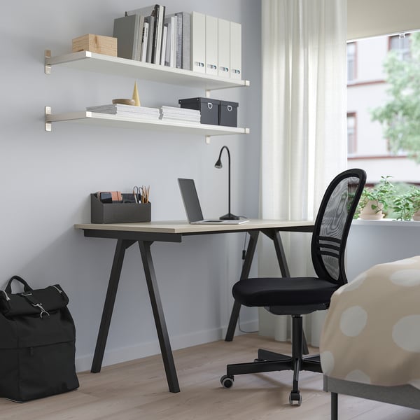 Bureau à domicile minimaliste moderne : bureau TROTTEN petit mais élégant avec chaise noire, ordinateur portable et étagères de rangement. Espace de travail soigné et efficace.