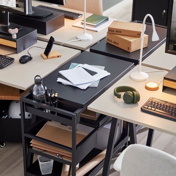 Espace de travail de bureau avec plusieurs bureaux, chacun équipé d’ordinateurs, d’écouteurs, de bouteilles d’eau, de blocs-notes et de lampes.