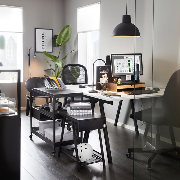 Configuration de bureau moderne avec chariot noir TROTTEN offrant espace de travail et rangement, soigneusement positionné sous le bureau.