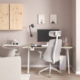 Bureau à domicile moderne : bureau en bois clair, chaise TROTTEN blanche, murs roses. Lampe intégrée, moniteur, haut-parleurs, écouteurs et art abstrait.