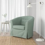 Fauteuil vert avec coussin et lampe sur tapis de jute. Ou, pour rester dans la limite de 150 caractères : fauteuil vert avec coussin et lampe sur tapis.