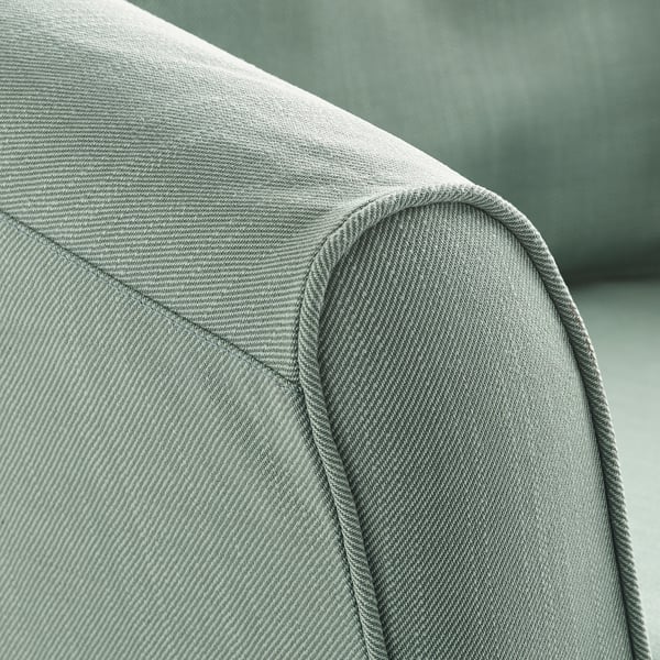 Gros plan d’un coin de fauteuil gris rembourré. Montre des coutures soignées et une texture de tissu de qualité.