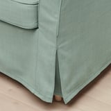 Gros plan sur les détails d’un fauteuil moderne et vert, montrant un tissu et des coutures de qualité.