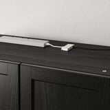 Chariot double prise de courant : sur une armoire en bois foncé, il ajoute 2 prises accessibles et 1 port USB pour charger plusieurs appareils.