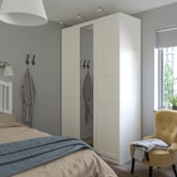 Chambre moderne avec armoire TYSSEDAL, miroir, murs gris, literie beige, chaise jaune.