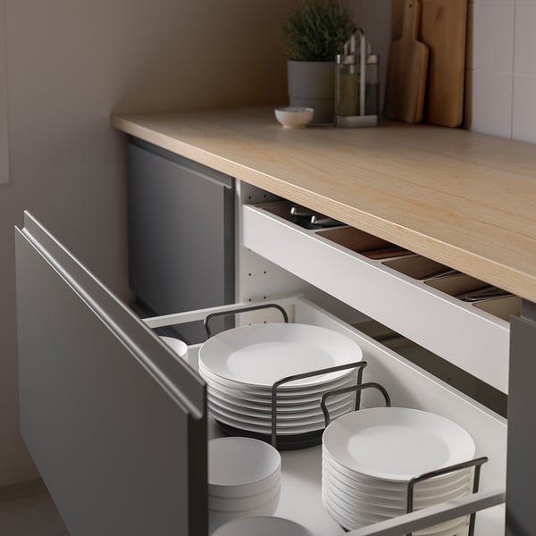 Tiroir de cuisine avec organisateur ouvert montrant des assiettes blanches empilées maintenues par des supports métalliques.