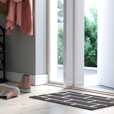 Tapis géométrique gris et blanc près de la porte, polypropylène.