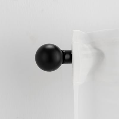 Un pinier VÄSENTLIG en forme de boule noire sur une tringle à rideaux. Finition mate, élégante, plastique recyclé. Petit, mais remarquable, apporte un style moderne.