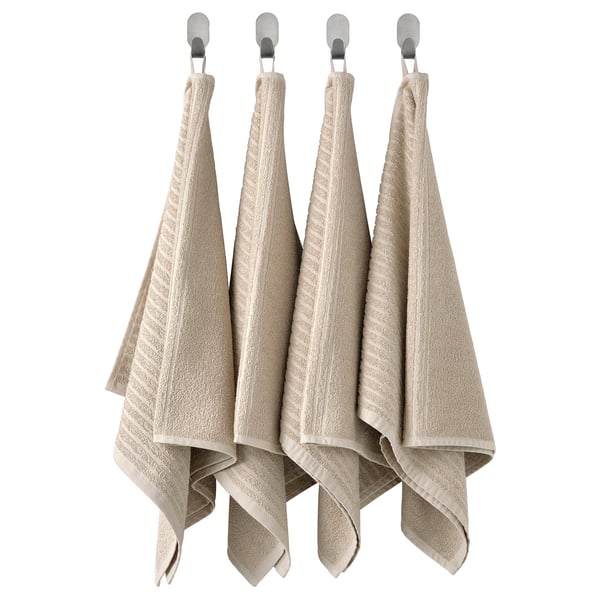 Quatre serviettes suspendues en coton beige avec des motifs linéaires.