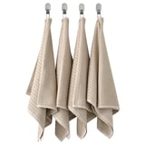 Quatre serviettes suspendues en coton beige avec des motifs linéaires.
