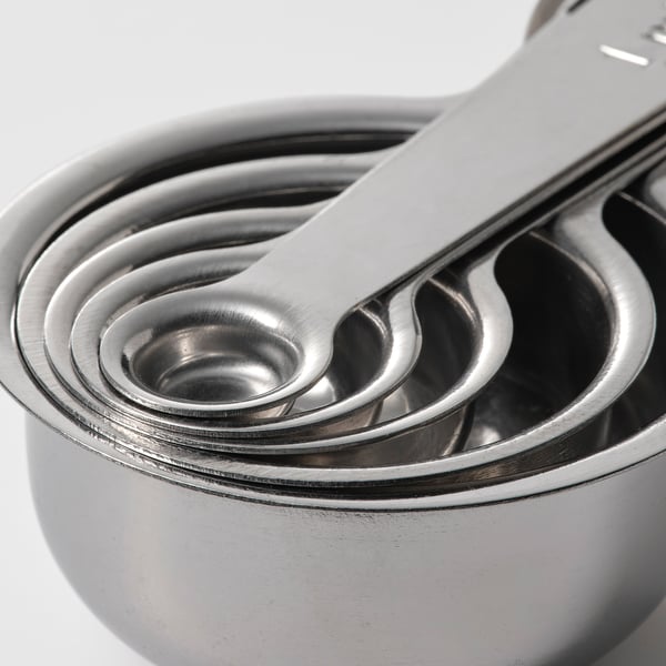 Cinq tasses à mesurer empilées en acier inoxydable, polies et brillantes, s’emboîtent soigneusement pour un rangement compact.