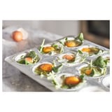 Moule à muffins en argent avec six compartiments remplis d’épinards et de tomates cerises prêts à cuire. Aluminium anodisé de haute qualité.