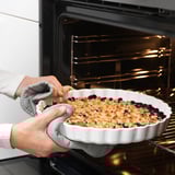 Le boulanger sort la tarte du four avec des mitaines.