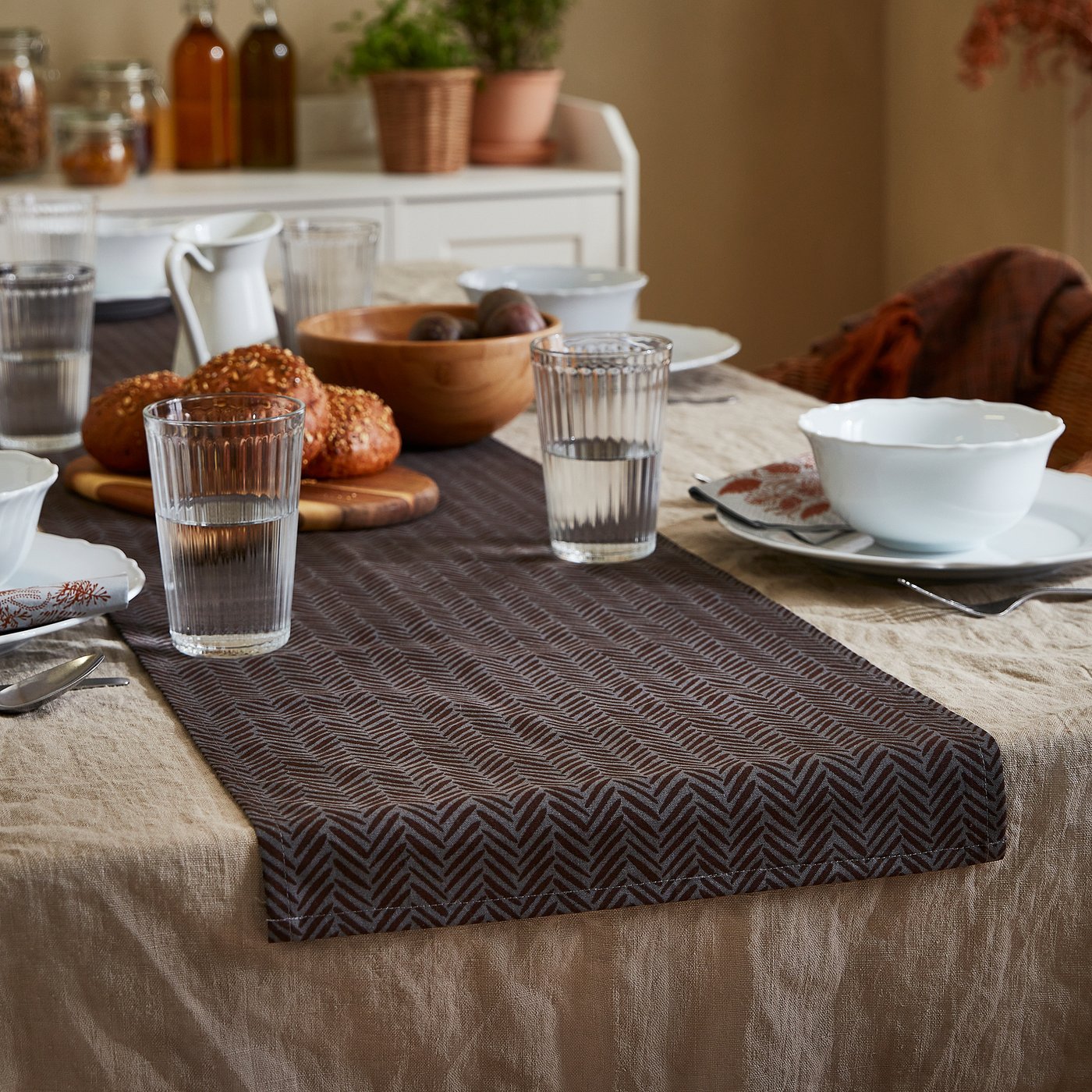 Table à manger avec verres VARDAGEN, bol à pain et chemin de table. Confortable et accueillant pour un repas.