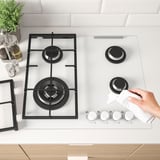 Nettoyage d’une plaque de cuisson à gaz avec allumage électronique et supports en fonte, assurant stabilité et nettoyage facile.