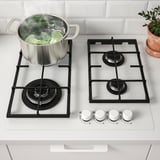 Cuisinière à gaz avec brocoli bouillant, commandes à l’avant.