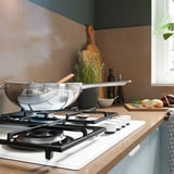 Cuisine moderne avec cuisinière à gaz blanche et wok en acier inoxydable.