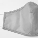 Gros plan d’un masque facial gris clair montrant des coutures de qualité et un tissu confortable.