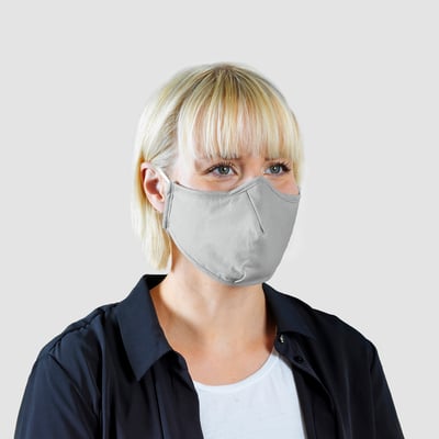 Femme blonde portant un masque facial non médical gris. Le masque présente un pince-nez intégré et une conception conforme.