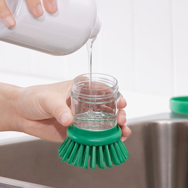 Verser du savon dans un pot à brosse pour laver la vaisselle.