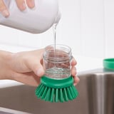 Verser du savon dans un pot à brosse pour laver la vaisselle.