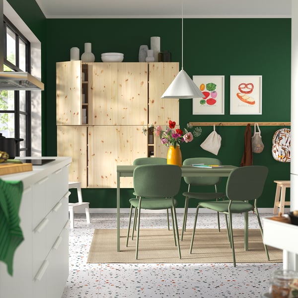 Cuisine moderne avec table à manger et chaises vertes VIHALS ; Armoires en bois, stylisées avec des plantes et des décors.