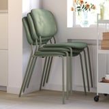 Empilement de 3 chaises de salle à manger vertes par radiateur.