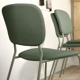 Chaises empilables en tissu vert avec pieds en métal, idéales pour les repas flexibles.