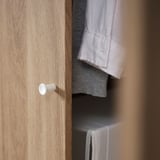 L’image montre une armoire moderne en bois VILHATTEN avec des boutons blancs. Il s’agit d’un design soigné, utilisant une feuille à motifs de chêne, alliant praticité et esthétique.