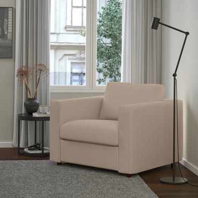 Salon moderne : fauteuil VIMLE beige, lampadaire noir, table d’appoint avec vase.