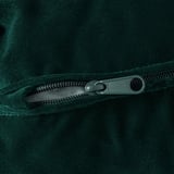 Un gros plan d’un tissu vert foncé avec une fermeture éclair noire, montrant la texture et la qualité.