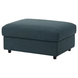 Un repose-pieds VIMLE en bleu foncé. Il est carré, recouvert d’un tissu texturé et a des pieds noirs. Il offre un espace de rangement sous le siège.