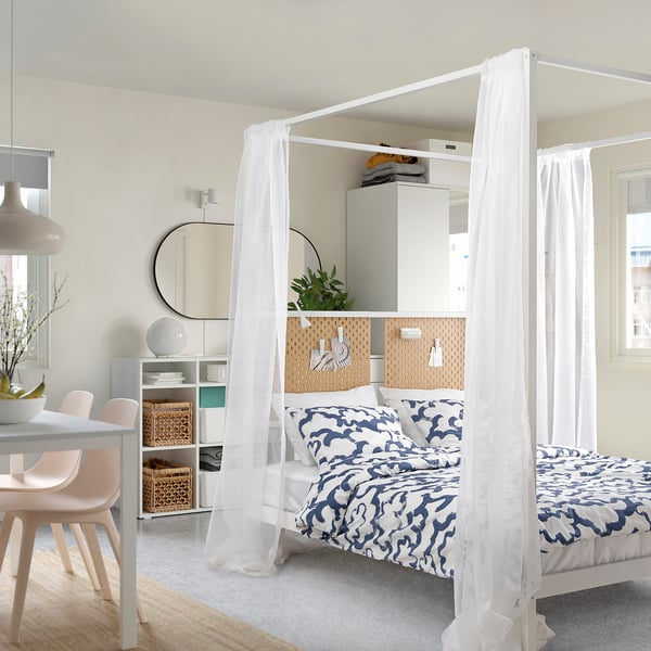 Chambre moderne avec lit à baldaquin VITARNA, literie bleue, panneau perforé et coin repas.
