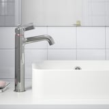 Robinet de salle de bain moderne avec finition chromée, poignée élégante et économie d’énergie monté sur un évier blanc.