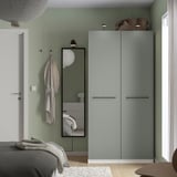 Chambre avec grande armoire YTBERG verte, lumière col de cygne, miroir, accessoires gris.