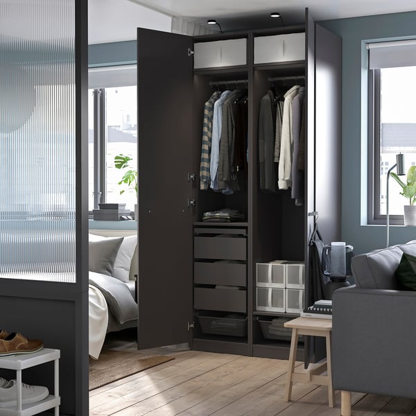 Chambre moderne avec armoire ouverte, avec cintres, tiroirs et une lampe LED YTBERG noire fixée sur le dessus, fournissant un éclairage réglable.