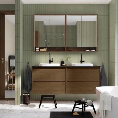 De ÄNGSJÖN badkamermeubel in bruin eikenhout, met dubbele wastafels en brede spiegels, voegt een moderne, minimalistische stijl toe aan de ruimte.